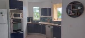 a kitchen with blue cabinets and a sink and a mirror at gite Calypso in Bouillante