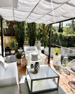 a patio with white furniture under a white umbrella at Estilosa casa golf in Gorraiz