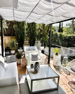un patio con mobili bianchi sotto un ombrellone bianco di Estilosa casa golf suites a Gorraiz