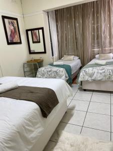 a bedroom with two beds and a tiled floor at Fj's place in Durban