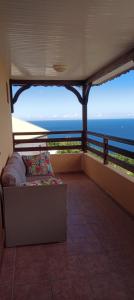 a couch on a balcony with a view of the ocean at gite Calypso in Bouillante
