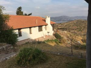 une maison blanche avec un toit orange sur une colline dans l'établissement Casa campestre – Lago azul, à Villa Parque Siquiman