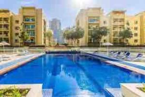 a large blue swimming pool with chairs and buildings at Charming 1BR in The Greens, Near Metro in Dubai