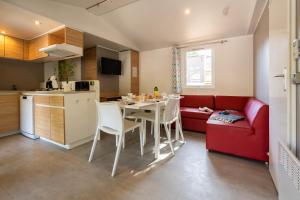 a kitchen and a living room with a table and a red couch at Camping Sunelia L'Argentière in Cogolin
