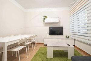 een witte kamer met een tafel en stoelen en een televisie bij Las Nieves Apartamento in Gijón