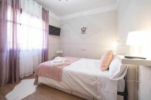 een witte slaapkamer met een bed en een lamp bij Las Nieves Apartamento in Gijón