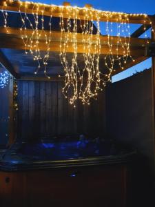 eine Reihe von Lichtern, die von einem Holzbalken hängen in der Unterkunft LE COTTAGE BARBIZONNAIS avec jacuzzi privé à partir de 10 ans in Barbizon