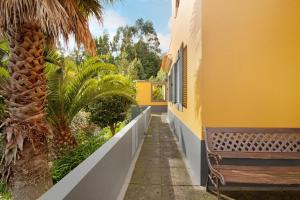 a yellow building with a bench and a palm tree at Casa Cristina in Junqueira