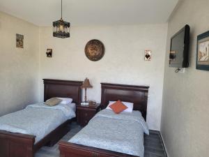 - une chambre avec 2 lits et une horloge murale dans l'établissement Jnane Ville Verte, à Casablanca