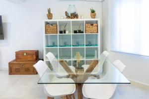 uma sala de jantar com uma mesa de vidro e cadeiras brancas em Apartamento completo a 5 minutos estación tren. em Córdoba