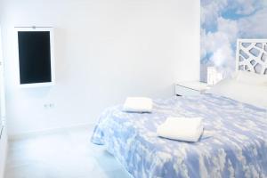 a white room with a bed with two towels on it at Apartamento completo a 5 minutos estación tren. in Córdoba