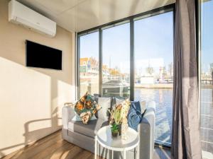 uma sala de estar com um sofá e uma grande janela em Inviting houseboat in Volendam with shared pool em Volendam