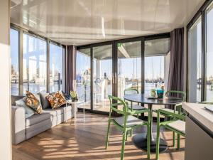 a living room with a couch and a table and chairs at Inviting houseboat in Volendam with shared pool in Volendam