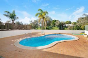 una piscina su un patio in mattoni con palme di Apartment Sunset a Almancil