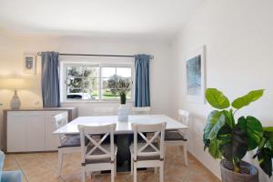 une salle à manger avec une table et des chaises blanches dans l'établissement Apartment Sunset, à Almancil