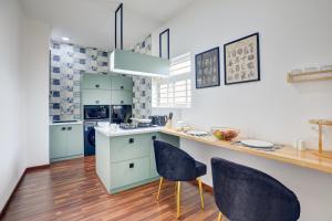 a kitchen with blue cabinets and a counter with chairs at Hoodo - HBR Layout Bangalore Apartments in Bengaluru +7 photos
