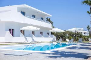 a white building with a swimming pool and chairs and umbrellas at Rosie's Studio 3 in Faliraki
