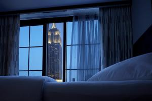 a bedroom with a window with a view of a skyscraper at Archer Hotel New York in New York