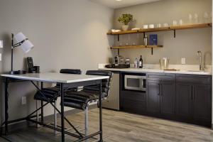 a kitchen with a table and chairs and a refrigerator at Archer Hotel Seattle/Redmond in Redmond