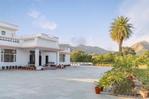 ein Gebäude mit einer Palme und Bergen im Hintergrund in der Unterkunft Jass Bagh Home stay Udaipur I swimming pool I wedding I 87oo2o5865 in Udaipur