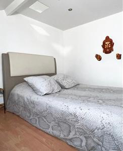 1 dormitorio con 1 cama y una máscara en la pared en SPA APPARTEMENT en Ermont