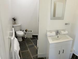 a white bathroom with a toilet and a sink at Sawyers Bed and Breakfast in Looe