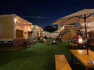 an outdoor patio with tables and umbrellas at night at Glamping Village LEAF in Mashiki