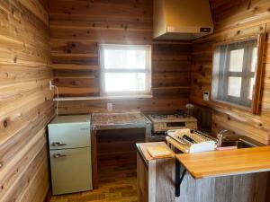 a kitchen with wooden walls and a refrigerator and a stove at Glamping Village LEAF in Mashiki