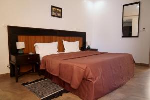 - une chambre avec un grand lit et une tête de lit en bois dans l'établissement Le Feto 2, à Dakar