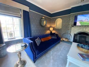 a living room with a blue couch and a fireplace at The Farmhouse in Pontefract