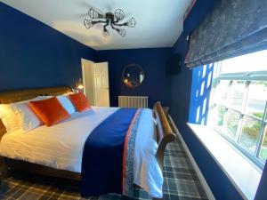 1 dormitorio con paredes azules y 1 cama con almohadas de color naranja en The Farmhouse, en Pontefract