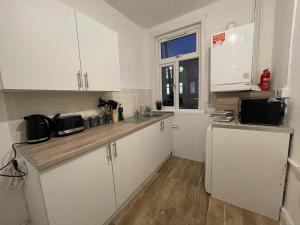 a small kitchen with white cabinets and a window at Beautiful 2 Bedroom On Tower Bridge in London