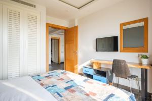 a bedroom with a bed and a desk and a tv at Degirmenburnu Residence in Bodrum City