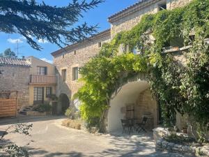 a stone building with an archway in a yard at Le Mas de la Pouzolle - Gîtes et chambre atypiques in Le Garn