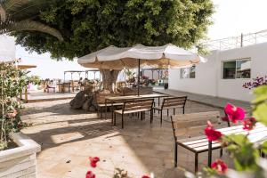 un patio con mesas, sillas y sombrillas en The Tree House Tenerife, en El Médano