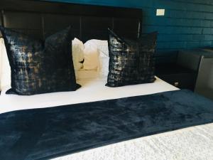uma cama com almofadas pretas e uma cabeceira preta em Skills Tree 58 Pty Ltd em Empangeni