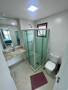 uma casa de banho com uma cabina de duche em vidro e um WC. em Nascer do sol 102 em Arraial do Cabo