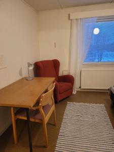 een woonkamer met een tafel en een rode stoel bij Kattilakosken vanha Pappila in Kärsämäki