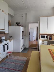 een keuken met witte apparatuur en een kamer met een tafel bij Kattilakosken vanha Pappila in Kärsämäki