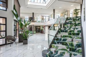 a lobby with a staircase with green plants at Occidental Roca Negra - Adults Only in Agaete