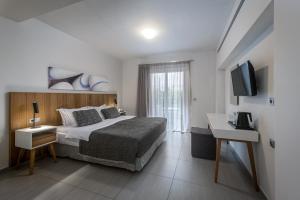 a hotel room with a bed and a television at More Meni Residence & Suites in Tigaki +80 photos