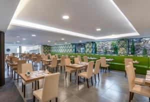 a restaurant with tables and chairs and a green wall at Occidental Roca Negra - Adults Only in Agaete