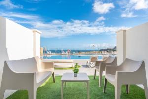 a patio with chairs and a table and a pool at Occidental Roca Negra - Adults Only in Agaete