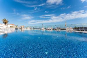a large swimming pool with chairs and a blue sky at Occidental Roca Negra - Adults Only in Agaete