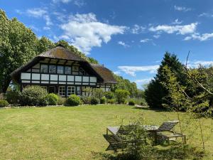 a house with a thatched roof and two chairs in a yard at Reetdachfachwerkvilla am Wiesengrund in Bergen auf Rügen