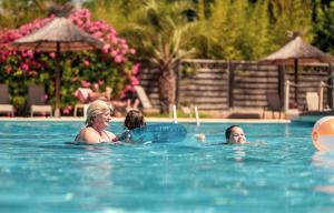 a woman and two children playing in a swimming pool at Camping Sunelia L'Argentière in Cogolin