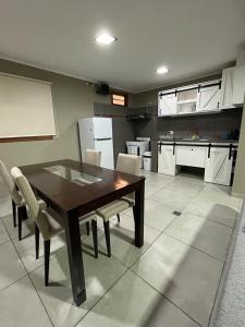 a kitchen with a wooden table and white chairs at Avalon Apartments in Puerto Iguazú