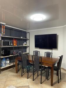 a dining room with a table and chairs and a flat screen tv at Fam_House in Bishkek