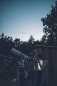 uma mulher segurando um telescópio no escuro em Le Refuge aux étoiles em Saint-Antonin
