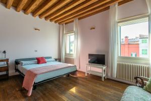 a bedroom with a bed and a tv and a window at Wondrous Palazzetto 1619 in Magical Burano Island in Burano